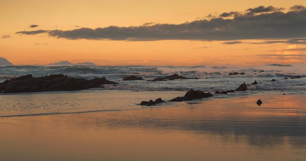 Belo pôr do sol com ondas no mar e nuvens ao fundo