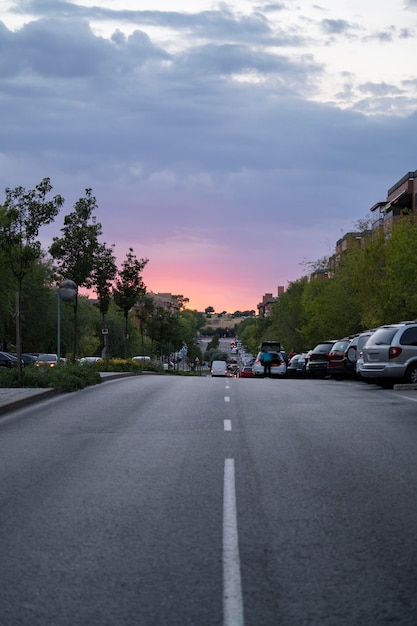 Belo pôr do sol em Alcobendas Espanha Sobre a estrada urbana pondo o sol atrás da cidade cheia de árvores