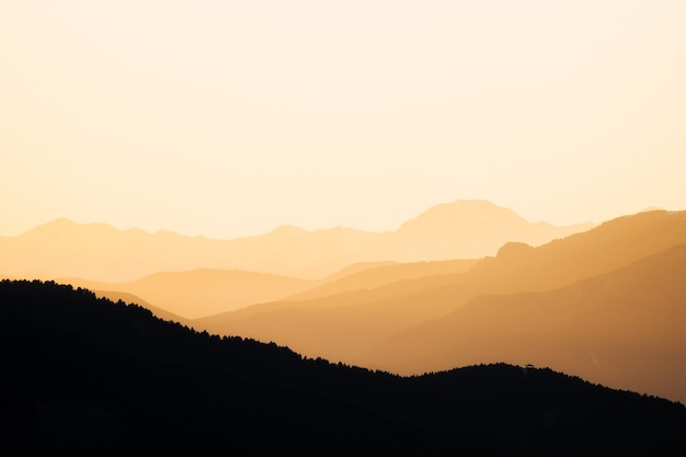 Belo pôr do sol em uma paisagem montanhosa. Últimos raios de sol do dia em ambiente calmo