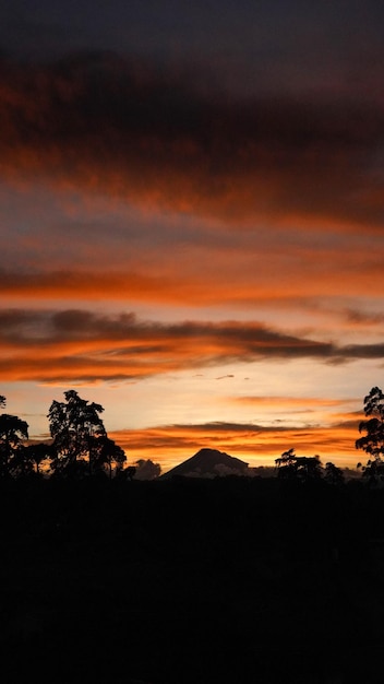 Foto belo pôr do sol laranja com um vulcão ao fundo