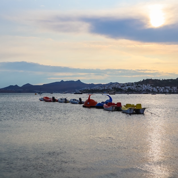 Belo pôr do sol na costa do Mar Egeu com ilhas e montanhas, barcos e catamarãs