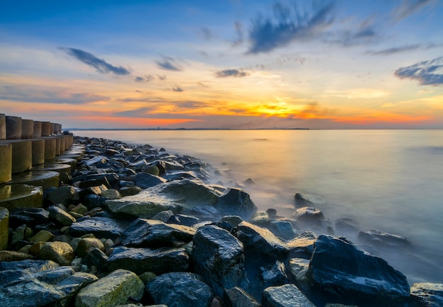 Belo pôr do sol na ilha de putri com um belo píer e quebra-mar ao longo da praia