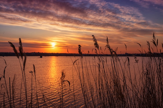 Belo pôr do sol no lago com nuvens e reflexões sobre a água