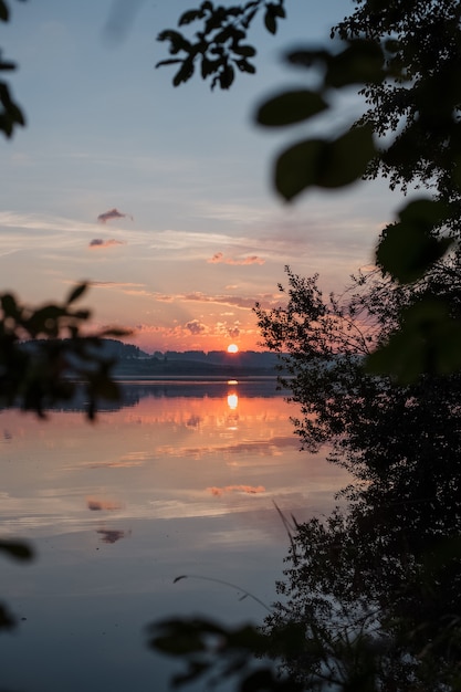 Belo pôr do sol no lago entre as árvores