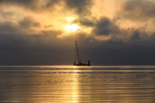 Foto belo pôr do sol no mar ártico. barcaça com guindaste. hora dourada. construção obras marítimas offshore. construção de barragem, guindaste, barcaça, draga.