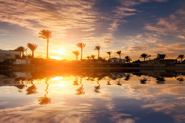 Belo pôr do sol romântico sobre uma praia arenosa e palmeiras Egito Hurghada