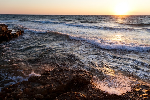 Belo pôr do sol sobre o litoral rochoso tempestuoso do Mar Negro na Crimeia em dia de verão