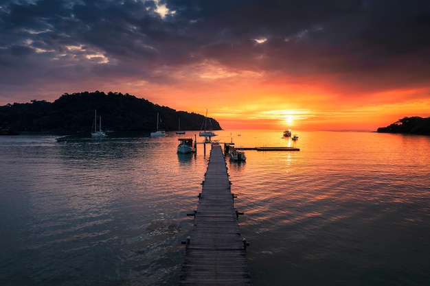 Belo pôr do sol sobre o mar tropical e barco de passeio de madeira e turista desfrutando na ilha de Koh Kood