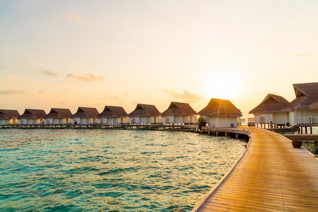 Belo pôr do sol tropical sobre a ilha maldivas com bangalô de água no hotel resort