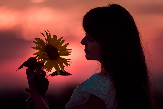 Belo pôr do sol vermelho com silhuetas de menina e girassol