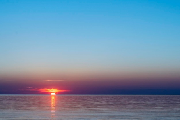 Belo pôr do sol vermelho no mar na superfície da água