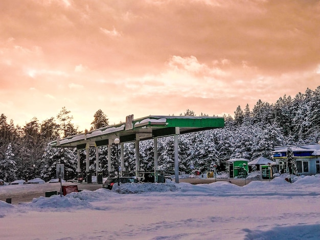 Belo posto de gasolina pequeno para reabastecer carros com combustível gasolina e diesel ao pôr do sol no inverno