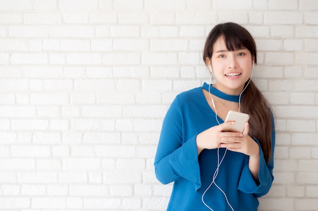 Belo retrato asiático jovem de pé feliz desfrutar e diversão ouvir música com fone de ouvido