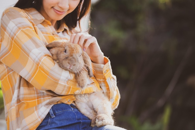 Belo retrato bonito de uma jovem mulher asiática com coelho fofo no conceito de animais de estimação e cuidados com animais fêmea feliz segurando coelho no campo ao ar livre da natureza com conceito de páscoa de amizade