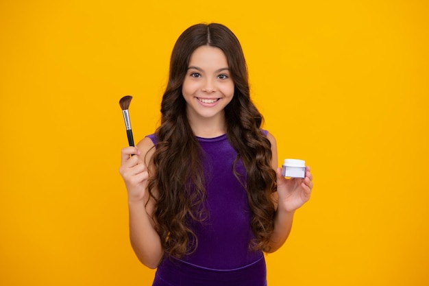 Foto belo retrato de artista de criança adolescente aplicar pó com pincel de maquiagem produtos de maquiagem beleza e cosméticos para adolescentes garota feliz enfrenta emoções positivas e sorridentes