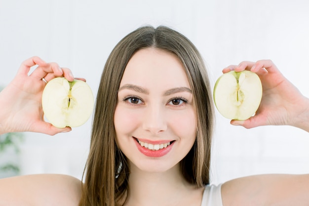 Belo retrato de close-up de jovem com metades de uma maçã. conceito de comida saudável. vitaminas e minerais.