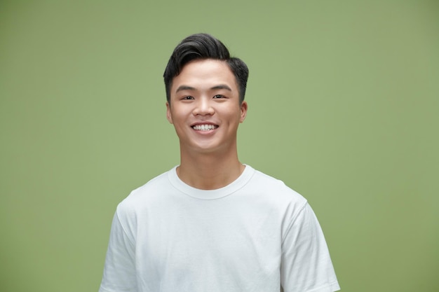 Belo retrato de um jovem asiático sorrindo isolado em fundo verde claro