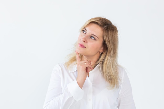 Belo retrato de uma jovem mulher bonita pensando olhando para a esquerda e sorrindo um pouco com um dedo no queixo isolado no fundo branco