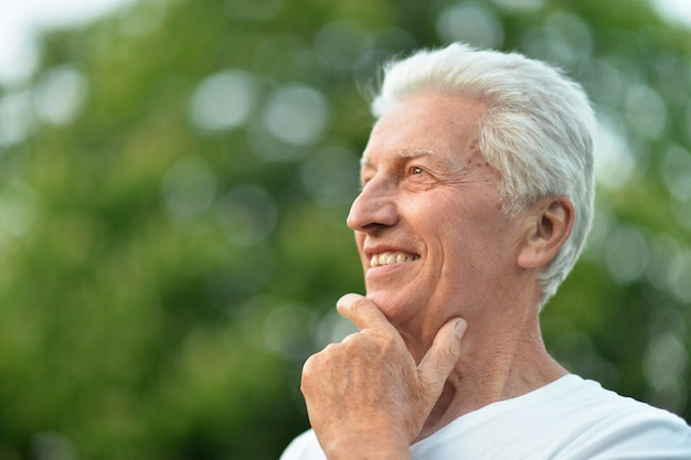 Belo sorridente homem sênior posando no parque de verão