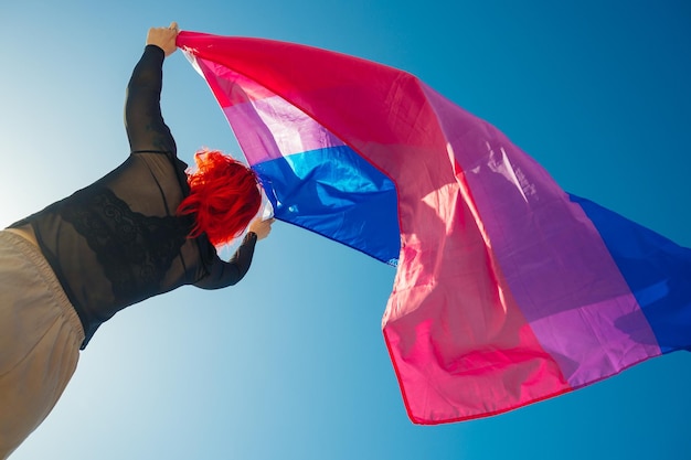 Belo tiro de ângulo baixo de uma mulher acenando com uma bandeira vermelha e azul