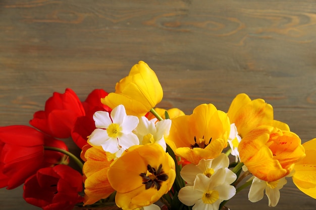 Belos buquês de tulipas e narcisos em fundo de madeira