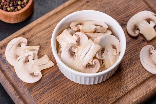 Belos jovens champignons brancos rasgados em fatias em um fundo escuro de concreto