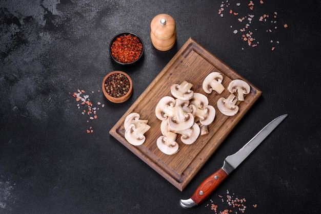 Belos jovens champignons brancos rasgados em fatias em um fundo escuro de concreto