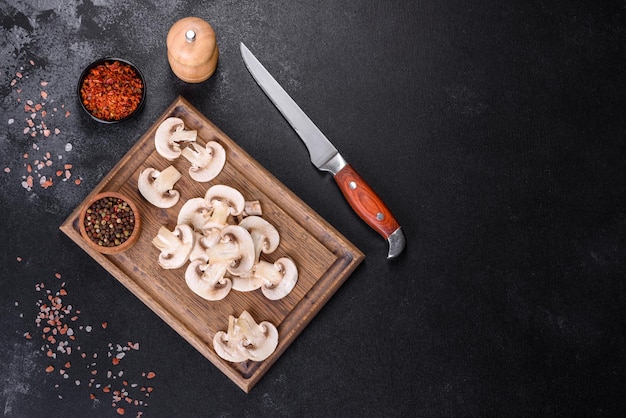 Belos jovens champignons brancos rasgados em fatias em um fundo escuro de concreto