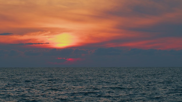 Belos pôr-do-sol sobre as ondas do oceano na superfície da água do mar ou do lago ao pôr- do- sol