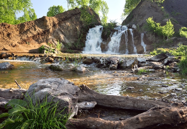 Belovsky Wasserfall im Frühjahr Ein kleiner Wasserfall zwischen den Felsen, umgeben von Birken