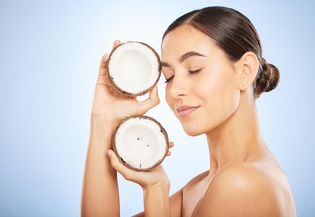 Bem-estar para a pele e rosto de mulher com coco em fundo azul para dermatologia, cuidados com o corpo e salão de spa de beleza e menina com frutas para produtos de beleza naturais, cosméticos e tratamento facial