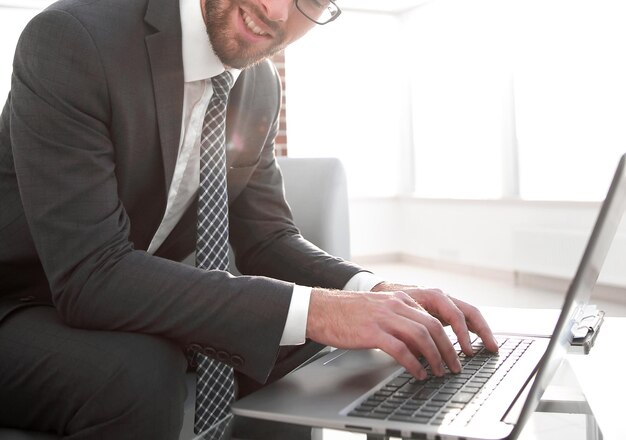 Bem sucedido jovem empresário digitando no laptop no local de trabalho