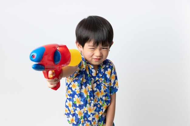 Bem-vindo a tailândia songkran festival, retrato do menino asiático vestindo camisa flor sorriu com pistola de água