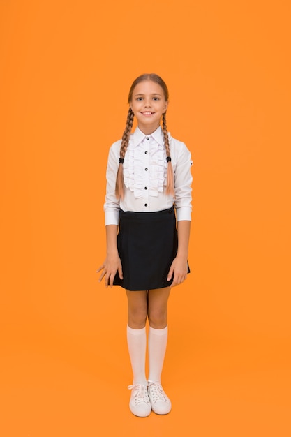 Bem vindo de volta à escola. Conceito de graduação. Educação primária. Colegial perfeita. Pequena colegial com um sorriso feliz. Garotinha bonita em uniforme escolar. Linda colegial com cabelo comprido.