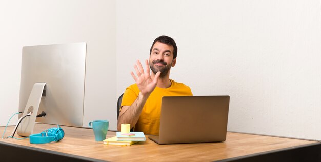 Bemannen Sie das Arbeiten mit Laptot in einem Büro, das fünf mit den Fingern zählt