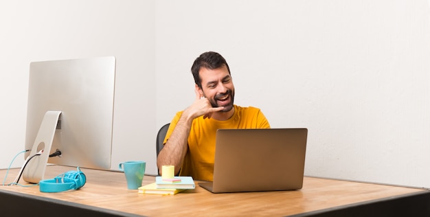 Bemannen sie das arbeiten mit laptot in einem büro, das telefongeste macht. ruf mich zurück zeichen