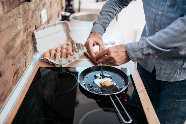 Bemannen Sie das Kochen der Eier zum Frühstück und an der Küche zu Hause stehen.