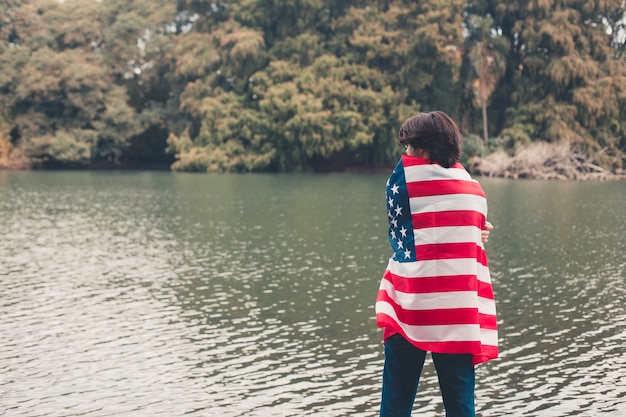 Bemannen Sie das Schützen der US-Flagge mit einem Hintergrundsee.