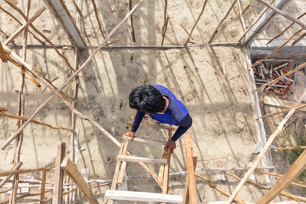 Bemannen Sie den tragenden Stiefel unter Verwendung der temporären hölzernen Treppe in der Baustelle, um auf und ab zu gehen.