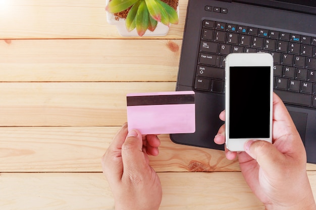 Bemannen Sie die Hände, die Kreditkarte halten und Smartphone für das on-line-Einkaufen verwenden