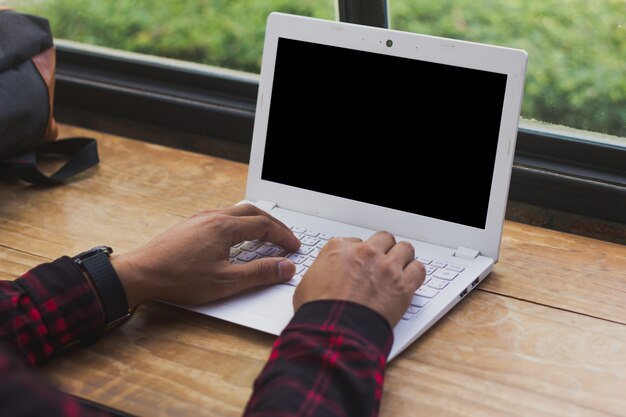 Bemannen Sie die Hand, die labtop Computer mit Schwarzem des leeren Bildschirms für Spott oben schreibt