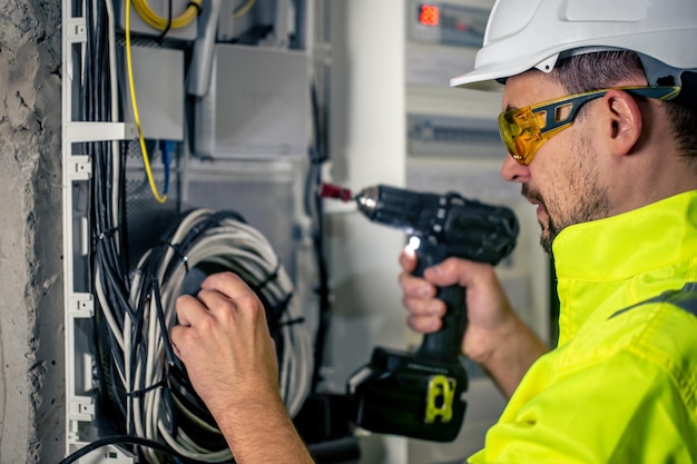 Bemannen Sie einen Elektrotechniker, der in einer Schalttafel mit Sicherungen arbeitet