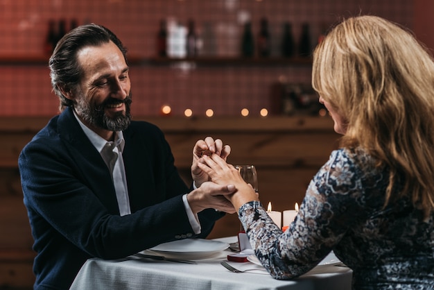 Bemannen Sie Heiratsantrag mit dem Ring seiner Freundin und setzen Sie den Ring an Hand in ein Restaurant