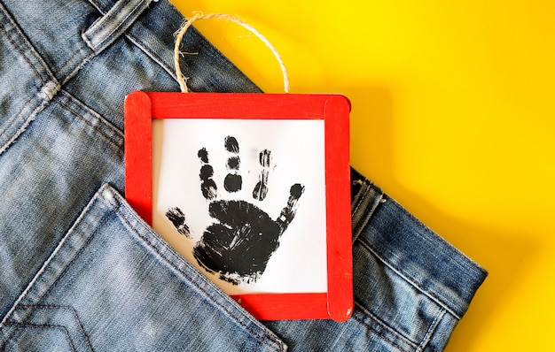 Bemannen Sie Jeansdetail mit handgemachtem Rahmen mit einer gestempelten Kinderhand in der Tasche