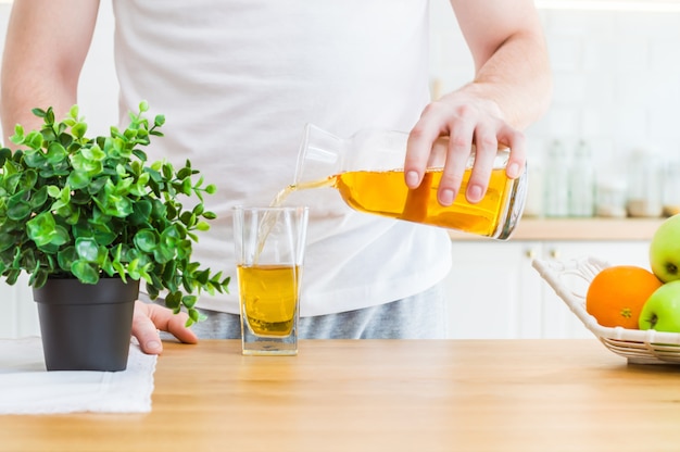 Bemannen Sie strömenden Apfelsaft vom Krug in Glas in der Küche.