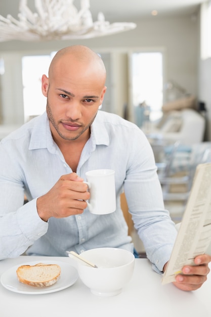 Bemannen Sie trinkenden Kaffee beim Zeitung zu Hause lesen