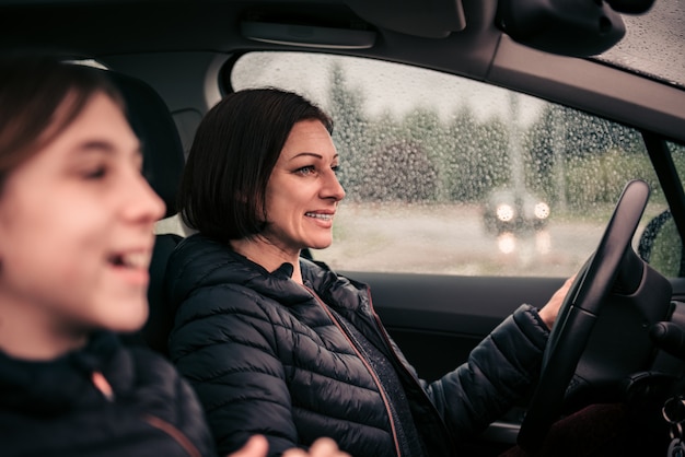 Bemuttern Sie das Fahren der Tochter im Passagiersitz an einem regnerischen Tag