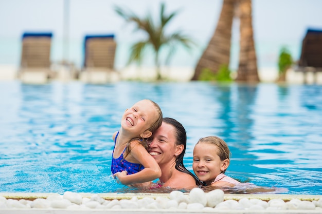 Bemuttern Sie und zwei Kinder, die Sommerferien im Luxusswimmingpool genießen