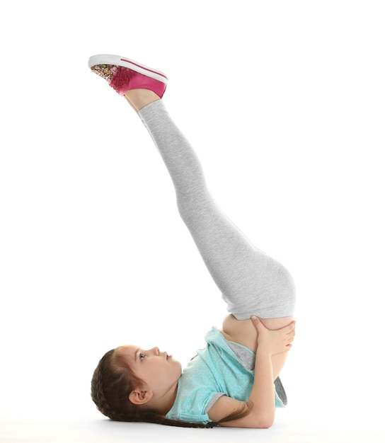 Übende Yogahaltung des kleinen netten Mädchens lokalisiert auf Weiß