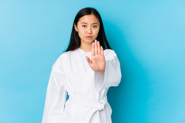 Übendes Karate der jungen chinesischen Frau lokalisierte Stellung mit der ausgestreckten Hand, die das Stoppschild zeigt und verhinderte Sie.